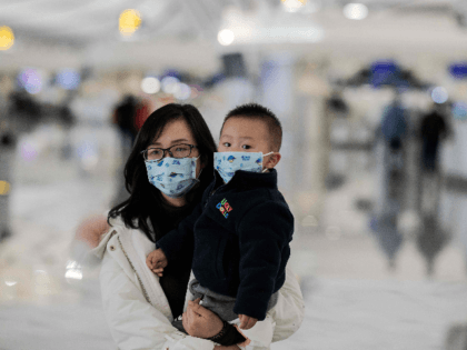 woman and a child wearing protective masks walk toward check-in counters at Daxing international airport in Beijing on January 21, 2020. - The death toll from a new China virus that is transmissible between humans rose to six, the mayor of Wuhan said in an interview with state broadcaster CCTV …