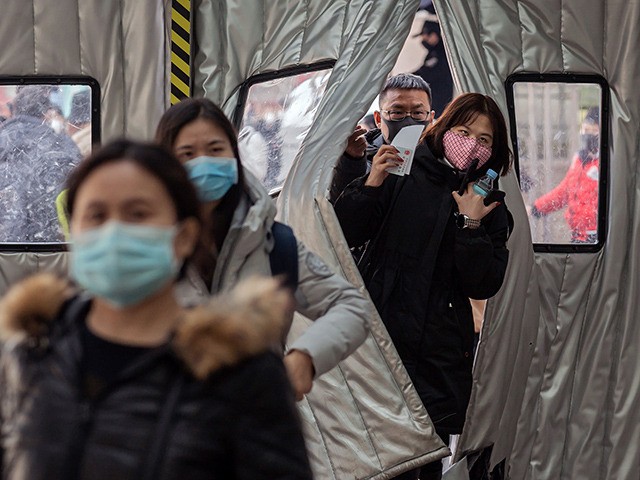 Passengers wearing protective masks walk into Beijing West Railway Station, in Beijing on