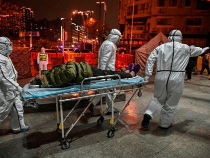 Medical staff members wearing protective clothing to help stop the spread of a deadly virus which began in the city, arrive with a patient at the Wuhan Red Cross Hospital in Wuhan on January 25, 2020. - The Chinese army deployed medical specialists on January 25 to the epicentre of …
