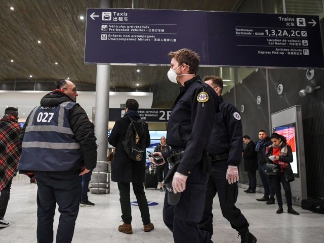 Policemen wearing protective face masks patrol at the arrival Terminal in Charles De Gaull