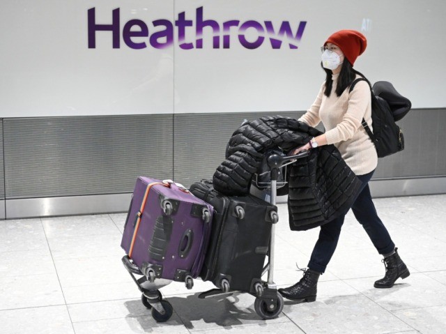 Passengers wear face masks as the push their luggage after arriving from a flight at Termi