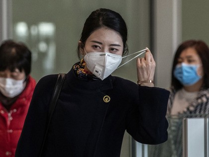 BEIJING, CHINA - JANUARY 30: A Chinese stewardess adjusts her mask after disembarking from