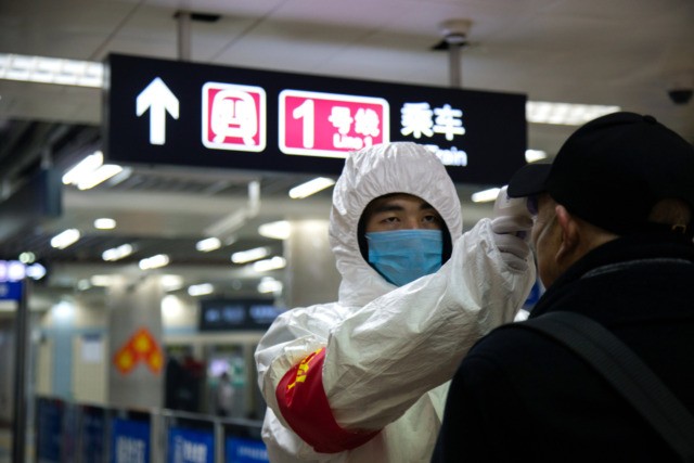 BEIJING, CHINA - JANUARY 26: A health worker checks the temperature of a man entering the