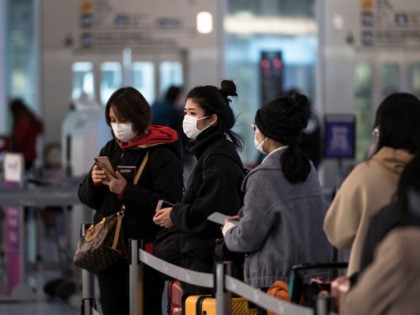 TOKYO, JAPAN - JANUARY 31: Passengers wearing masks wait at Spring Airlines' check-in counter to take a flight bound for Wuhan at Haneda airport on January 31, 2020 in Tokyo, Japan. The Chinese government arranged a charter flight operated by Spring Airlines for tourists from Wuhan to return to the …