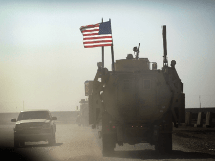 NASIRIYAH, IRAQ - DECEMBER 02: A U.S. Army armored vehicle flies an American flag as it provides security escort for a convoy of vehicles pulling equipment that is heading to Kuwait from Camp Adder as the Army continues to send it's soldiers and equipment home and the base is prepared …
