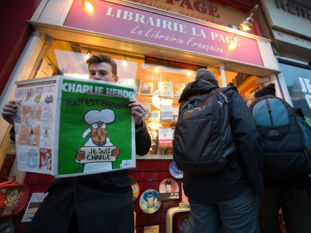 A customer poses with a copy of the French satirical magazine Charlie Hebdo, as it goes on