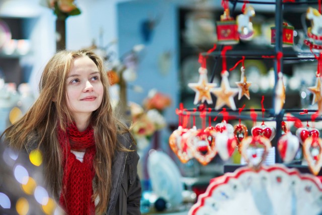Girl at Christmas market looking at shop windows decorated for Christmas.