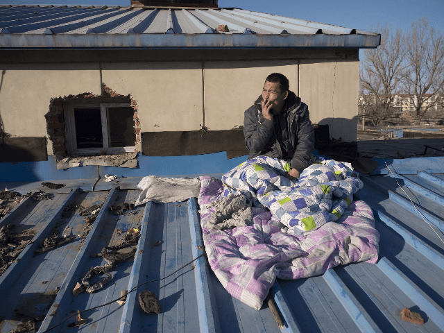 n this picture taken on December 11, 2017, a migrant worker who was evicted from his room in a low-income housing area sits on the roof of a house where he has been staying, as he waits to receive his salary before returning to his home in the south of …
