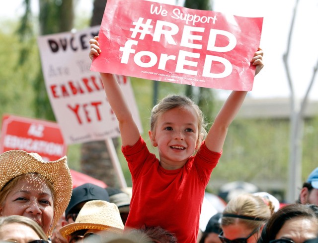 PHOENIX, AZ - APRIL 26: A young student holds up a sign in support of Arizona teachers during a #REDforED rally in front of the State Capitol on April 26, 2018 in Phoenix, Arizona. Teachers state-wide staged a walkout strike on Thursday in support of better wages and state funding …