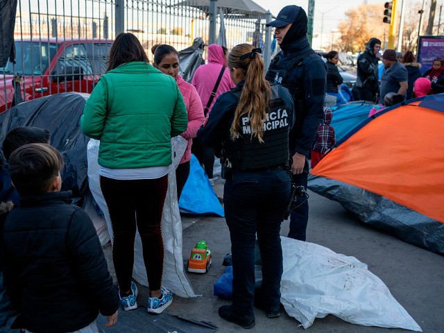 Juarez municipal police speak to asylum seekers camped out near Paso del Norte Internation