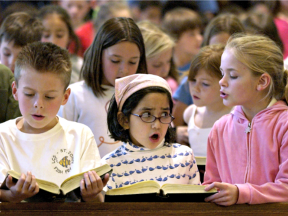 Lawrence Catholic School students Adam Wagner, 8, left, Isabel Cartter, 6, center, and Marlee Bird, 8, right, along with about 300 classmates sing songs during a prayer service for an ailing Pope John Paul II at St. John the Evangelist Church in Lawrence, Kan. Friday, April 1, 2005. (AP Photo/Charlie …