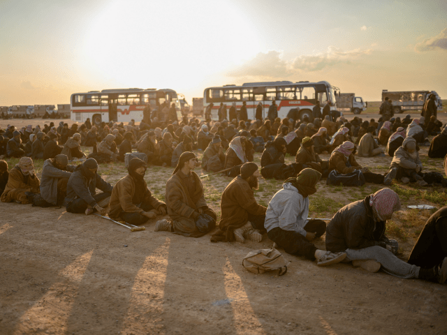 Men suspected of being Islamic State (IS) fighters wait to be searched by members of the Kurdish-led Syrian Democratic Forces (SDF) after leaving the IS group's last holdout of Baghouz, in Syria's northern Deir Ezzor province on February 22, 2019. (Photo by Bulent KILIC / AFP) (Photo credit should read …