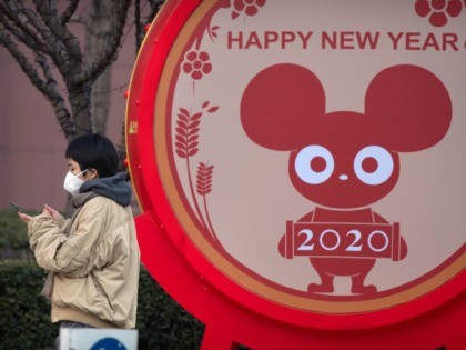 A woman wears a face mask standing near a display for the upcoming Lunar New Year, the Yea