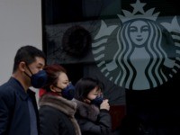People wearing protective face masks walk past a closed Starbucks coffee shop at a grocery in Beijing on January 29, 2020. - People in Beijing and across China are donning masks, spraying antiseptic and staying off the streets in a battle to halt the spread of a viral outbreak that …