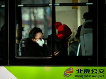 A mask-clad commuter rides a bus in Beijing on January 21, 2020. - The number of people in