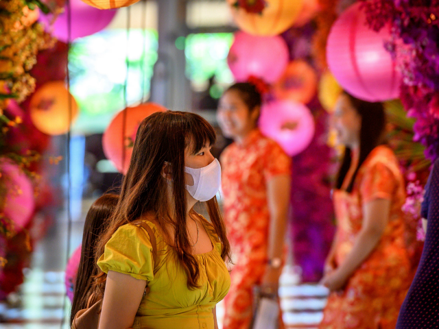A woman with a face mask walks in a shop decorated for the Chinese Lunar New Year in Bangk