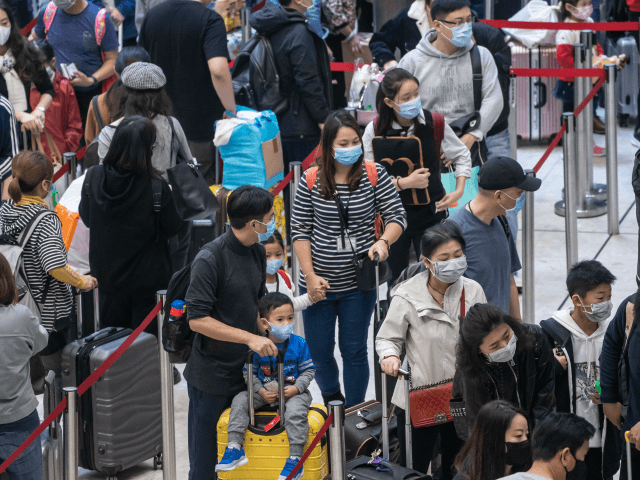 HONG KONG, CHINA - JANUARY 23: Travellers wearing face mask wait in line at the departure