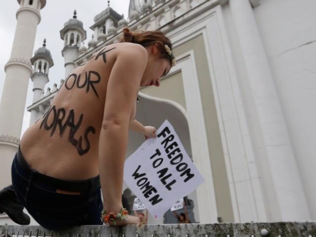 An activist of women's rights organization Femen climbs over a fence in front of a mosque during a protest in Berlin, Thursday, April 4, 2013. The radical feminists, calling for more sexual freedom for Arab women, were protesting in support of a young Tunisian woman who received online death threats …