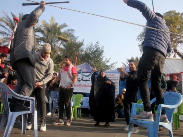 Iraqi anti-government protesters celebrate outside their protest tents in Baghdad's Tahrir