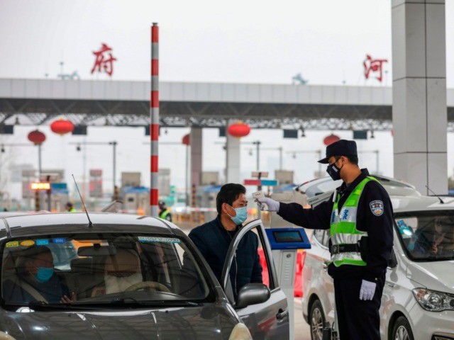 A police officer checks the temperature of a driver at a highway in Wuhan, in China's cent