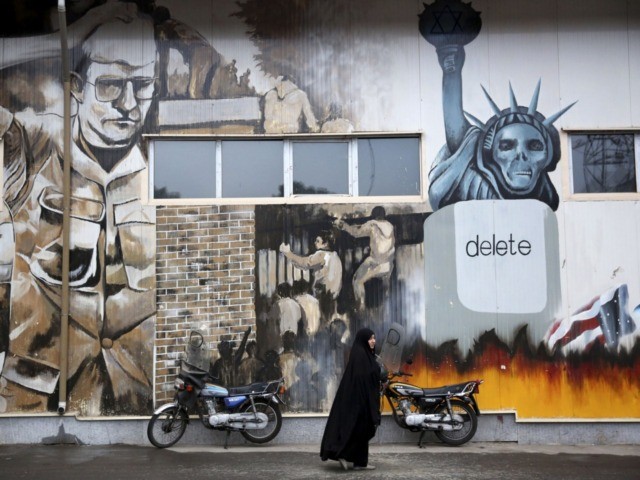 An unidentified woman walks under an anti-U.S. graffiti painted on the walls of the former