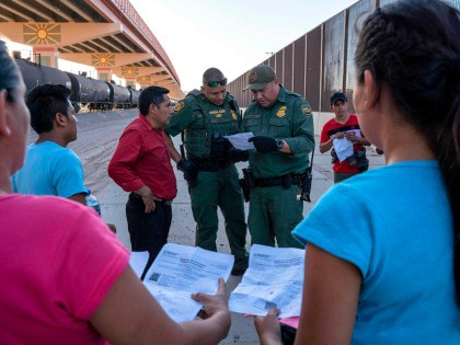 TOPSHOT - US Customs and Border Protection agents check documents of a small group of migrants, who crossed the Rio Grande from Juarez, Mexico, on May 16, 2019, in El Paso, Texas. - About 1,100 migrants from Central America and other countries are crossing into the El Paso border sector …