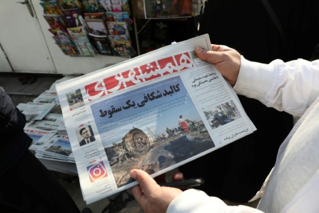 An Iranian holds a newspaper with a picture of the debris of the Ukrainian plane that crashed in Tehran on January 8, 2020, outside a news stand in the Islamic republic's capital Iran's 'catastrophic mistake': Speculation, pressure, then admission