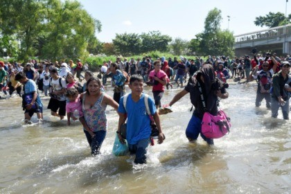Central American migrants - mostly Hondurans, travelling on caravan to the US- cross the Suichate River, the natural border between Tecum Uman, Guatemala and Ciudad Hidalgo, Mexico, on January 20, 2020 Troops fire gas as migrants try to storm into Mexico