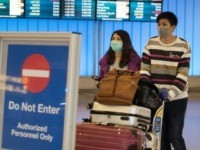 Passengers wear masks to protect against the spread of the novel coronavirus as they arrive at Los Angeles International Airport