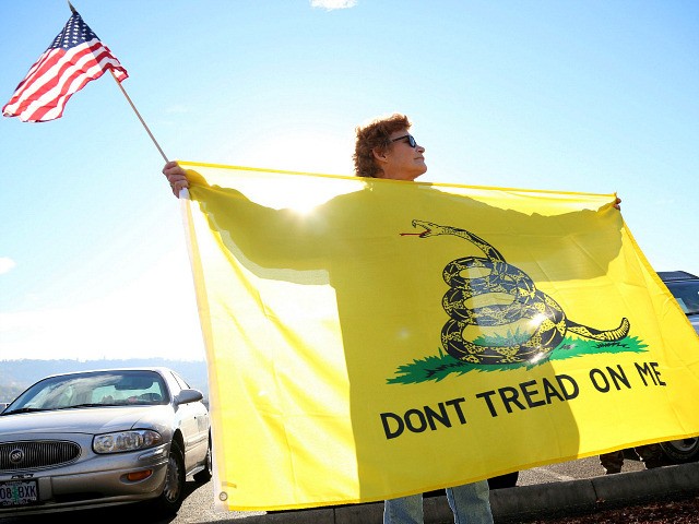 Leslie Corp holds up an American flag and the Gadsden flag while waiting outside of Rosebu