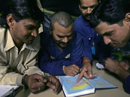 Baghdad, IRAQ: Immigrant workers look at a map of the world to locate Iraq at a US army base in Mahmudiyah in the southern outskirts of Baghdad, early December 2005. Some 6,000 to 7,000 immigrants from India, Sri Lanka, and Philippines work on US Army bases in Iraq for a …