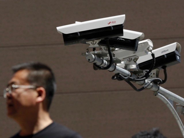 People walk by Chinese-made surveillance cameras installed along a street in Beijing, Thur