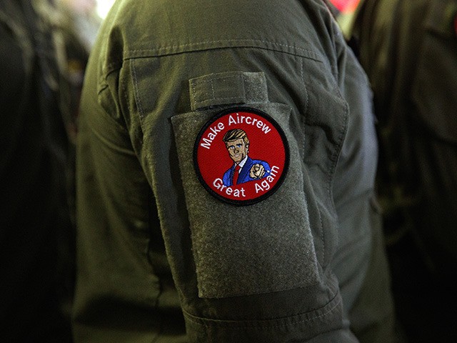 A service member wears a patch that says "Make Aircrew Great Again" as they listen to Pres