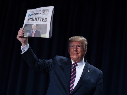 President Donald Trump holds up a newspaper with the headline that reads "ACQUITTED" during the 68th annual National Prayer Breakfast, at the Washington Hilton, Thursday, Feb. 6, 2020, in Washington. (AP Photo/ Evan Vucci)