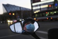 BEIJING, CHINA - FEBRUARY 22: A Chinese man is seen in the side mirror of his scooter as he wears a protective mask while waiting at a red light on February 22, 2020 in Beijing, China. The number of cases of the deadly new coronavirus COVID-19 being treated in China …