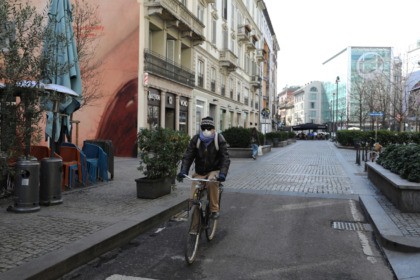 MILAN, ITALY - FEBRUARY 26: A man wearing a mask rides a bicycle on an empty Corso Garibal