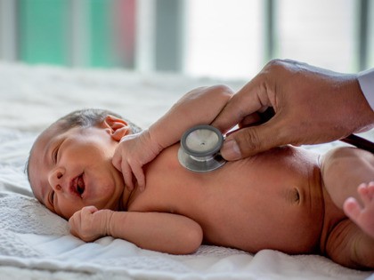 Soft blur of the doctor hands use stethoscope to check newborn baby health and take care him or cure the disease or disorder.