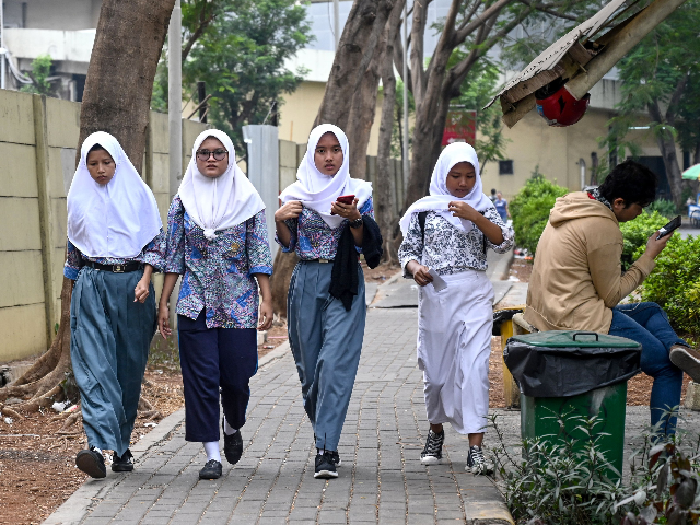 A group of young Muslims wearing hijabs make their way along a street in Jakarta on September 19, 2019. - Indonesia is set to vote on a plan to outlaw gay and pre-marital sex while beefing up its blasphemy laws in a shakeup fuelled by religious conservatism and slammed by …