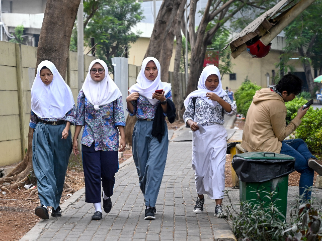 A group of young Muslims wearing hijabs make their way along a street in Jakarta on Septem