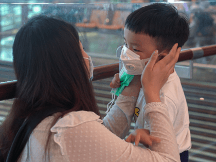 A woman wearing a mask helps her son put on his mask at Changi Airport on January 25, 2020 in Singapore. Yesterday Singapore confirmed its third case of the deadly coronavirus which emerged last month in the city of Wuhan in China. (Photo by Ore Huiying/Getty Images)