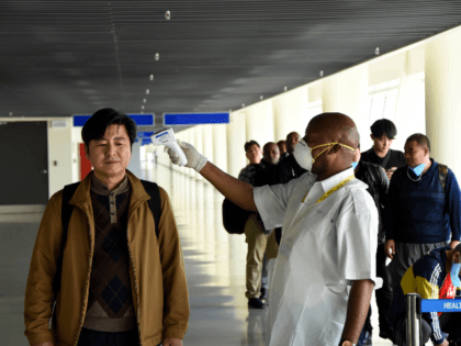 A health officer measures the body temperature of a passenger arriving from China at the J