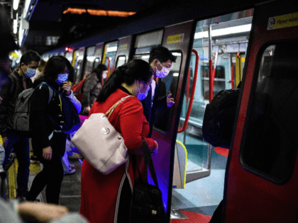 Passengers wear protective face masks as they board a Hong Kong bound MTR train to Hong Ko