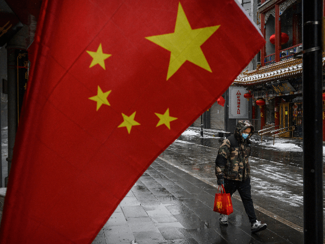 A Chinese man wears a protective mask as he walks during a snowfall in an empty and shuttered commercial street on February 5, 2020 in Beijing, China.