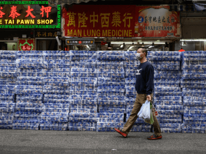 A man wearing a protective face mask walks past stacks of toilet paper for sale in the Tsuen Wan district of Hong Kong on February 8, 2020. - Hong Kong has been hit by a wave of panic-buying in recent days with supermarket shelves frequently emptied of crucial goods such …