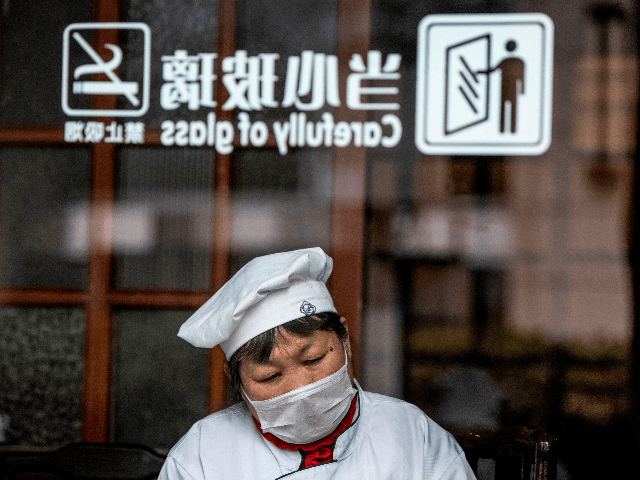 A restaurant employee has a rest at a table in Shanghai on February 8, 2020. - The new coronavirus that emerged in a Chinese market at the end of last year has killed more than 700 people and spread around the world. (Photo by NOEL CELIS / AFP) (Photo by …