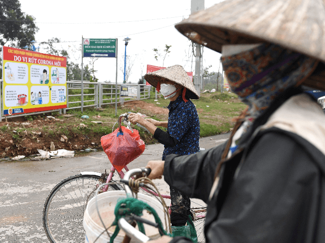 Local residents wearing protective facemasks amid concerns of the COVID-19 coronavirus wait to pass through a checkpoint in Son Loi commune in Vinh Phuc province on February 13, 2020. - Villages in Vietnam with 10,000 people close to the nation's capital were placed under quarantine on February 13 after six …