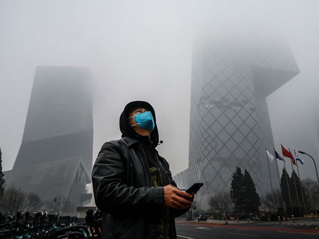 BEIJING, CHINA - FEBRUARY 13: A Chinese man wears a protective mask as he stands near the CCTV building in fog and pollution during rush hour in the central business district on February 13, 2020 in Beijing, China. The number of cases of the deadly new coronavirus COVID-19 rose to …