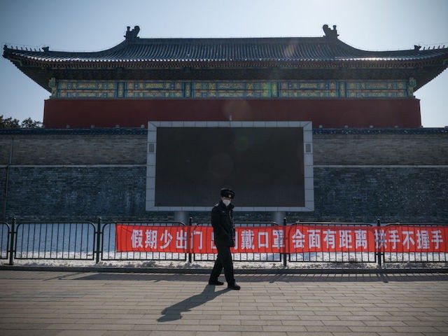 BEIJING, CHINA - FEBRUARY 15: A security guard walks past a propaganda banner saying "Do Not Leave Home Often During Holidays, Wear a Mask When Going Out, Keep a Distance and Do Not Shake Hands When Meeting" on February 15, 2020 in Temple of Heaven Park, Beijing, China. (Photo by Andrea Verdelli/Getty Images)