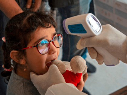 A member of a medical team takes a the temperature of a young Iraqi traveller at the Shalamjah border crossing, some 15 kms southeast of the city of Basra, upon their return from Iran on February 21, 2020. - Iran reported two more deaths among 13 new cases of coronavirus …