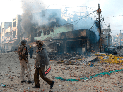 Policeman stand in front of vandalised shops following clashes between supporters and opponents of a new citizenship law, at Bhajanpura area of New Delhi on February 24, 2020, ahead of US President arrival in New Delhi. - Fresh clashes raged in New Delhi in protests over a contentious citizenship law …